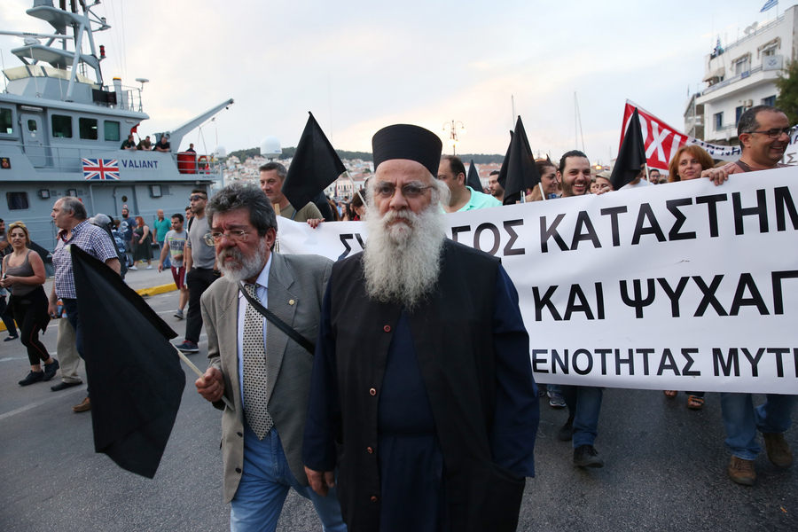Διαδηλωτές κρατώντας πανό και μαύρες σημαίες σε συγκέντρωση διαμαρτυρίας έξω από το Αίθριο της Γενικής Γραμματείας Αιγαίου, όπου θα μιλήσει ο πρωθυπουργός Αλέξης Τσίπρας στο 14ο Περιφερειακό Συνέδριο για την Παραγωγική Ανασυγκρότηση, στη Μυτιλήνη, την Πέμπτη 3 Μαΐου 2018. Με κινητοποιήσεις, απεργίες και κλειστά καταστήματα αντιδρούν κάτοικοι και φορείς της Λέσβου στην επίσκεψη του πρωθυπουργού Αλέξη Τσίπρα για να συμμετάσχει στο 14ο Αναπτυξιακό Συνέδριο Βορείου Αιγαίου. Πάγιο αίτημα των κατοίκων και των φορέων είναι η άμεση αποσυμφόρηση από τον μεγάλο αριθμό προσφύγων και μεταναστών, αλλά και η διατήρηση των μειωμένων συντελεστών ΦΠΑ. ΑΠΕ ΜΠΕ/ΑΠΕ ΜΠΕ/ΟΡΕΣΤΗΣ ΠΑΝΑΓΙΩΤΟΥ