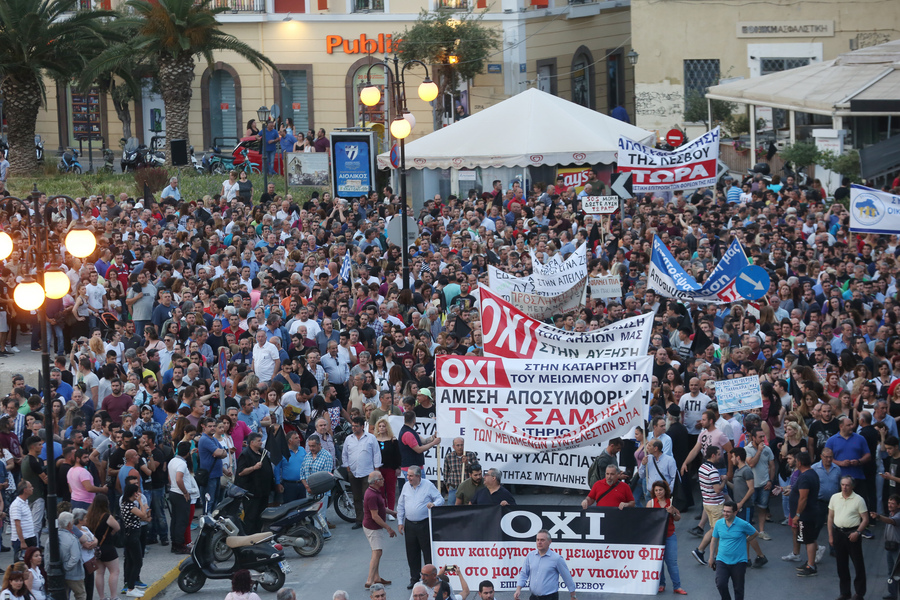 Διαδηλωτές κρατώντας πανό και σημαίες σε συγκέντρωση διαμαρτυρίας έξω από το Αίθριο της Γενικής Γραμματείας Αιγαίου, όπου θα μιλήσει ο πρωθυπουργός Αλέξης Τσίπρας στο 14ο Περιφερειακό Συνέδριο για την Παραγωγική Ανασυγκρότηση, στη Μυτιλήνη, την Πέμπτη 3 Μαΐου 2018. Με κινητοποιήσεις, απεργίες και κλειστά καταστήματα αντιδρούν κάτοικοι και φορείς της Λέσβου στην επίσκεψη του πρωθυπουργού Αλέξη Τσίπρα για να συμμετάσχει στο 14ο Αναπτυξιακό Συνέδριο Βορείου Αιγαίου. Πάγιο αίτημα των κατοίκων και των φορέων είναι η άμεση αποσυμφόρηση από τον μεγάλο αριθμό προσφύγων και μεταναστών, αλλά και η διατήρηση των μειωμένων συντελεστών ΦΠΑ. ΑΠΕ ΜΠΕ/ΑΠΕ ΜΠΕ/ΟΡΕΣΤΗΣ ΠΑΝΑΓΙΩΤΟΥ